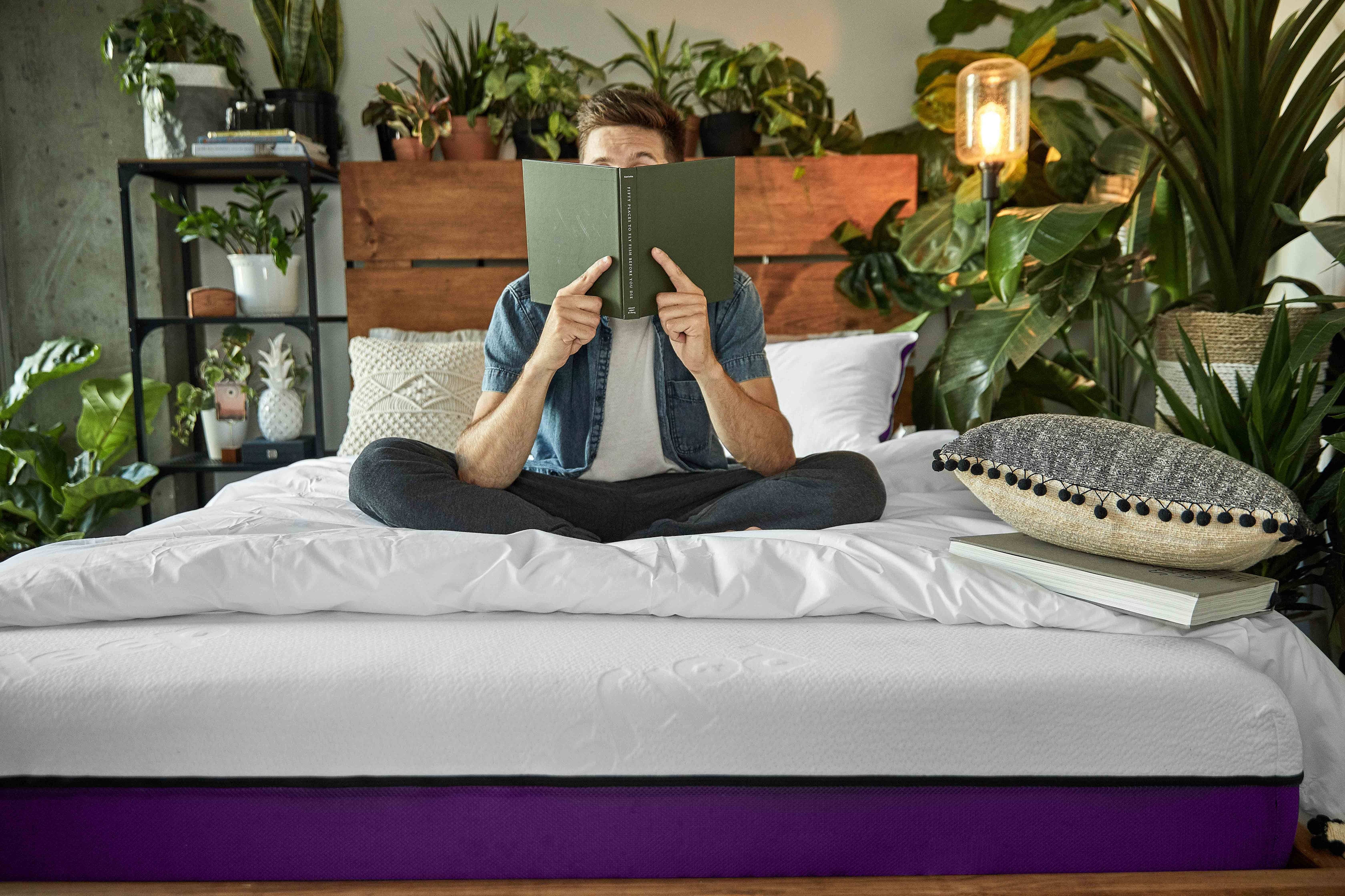 Young man reading a book while sitting on its Polysleep mattress