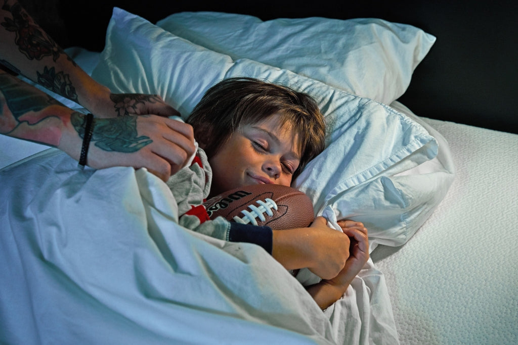 Young boy sleeping with an american football in his hands