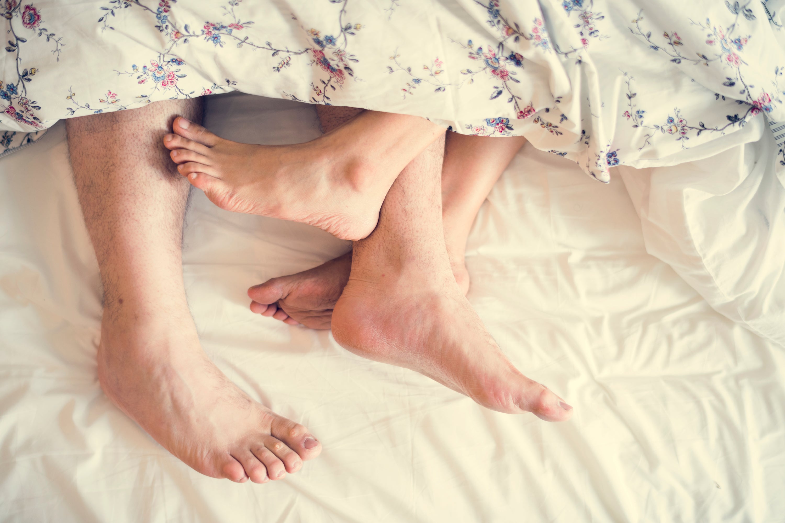 Vue aérienne de deux paires de pieds qui dépassent d'une couette