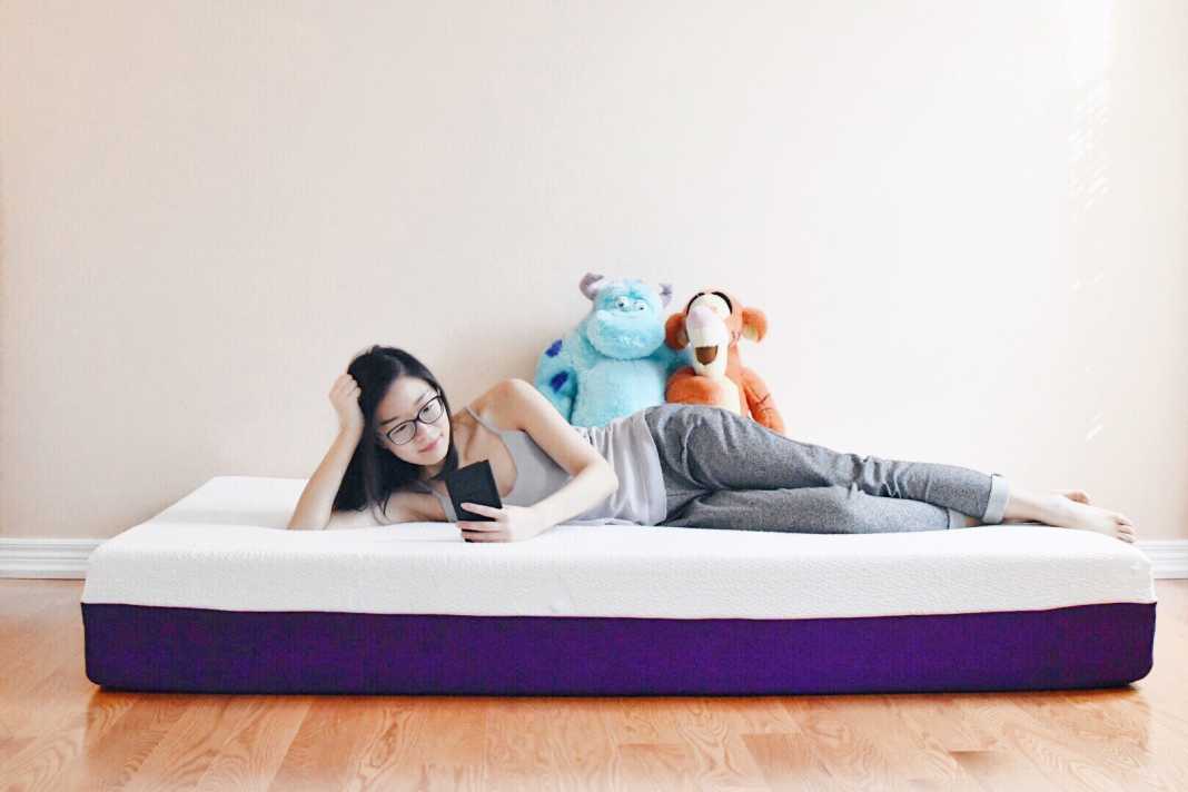 Woman lying on her Polysleep mattress looking at her cellphone