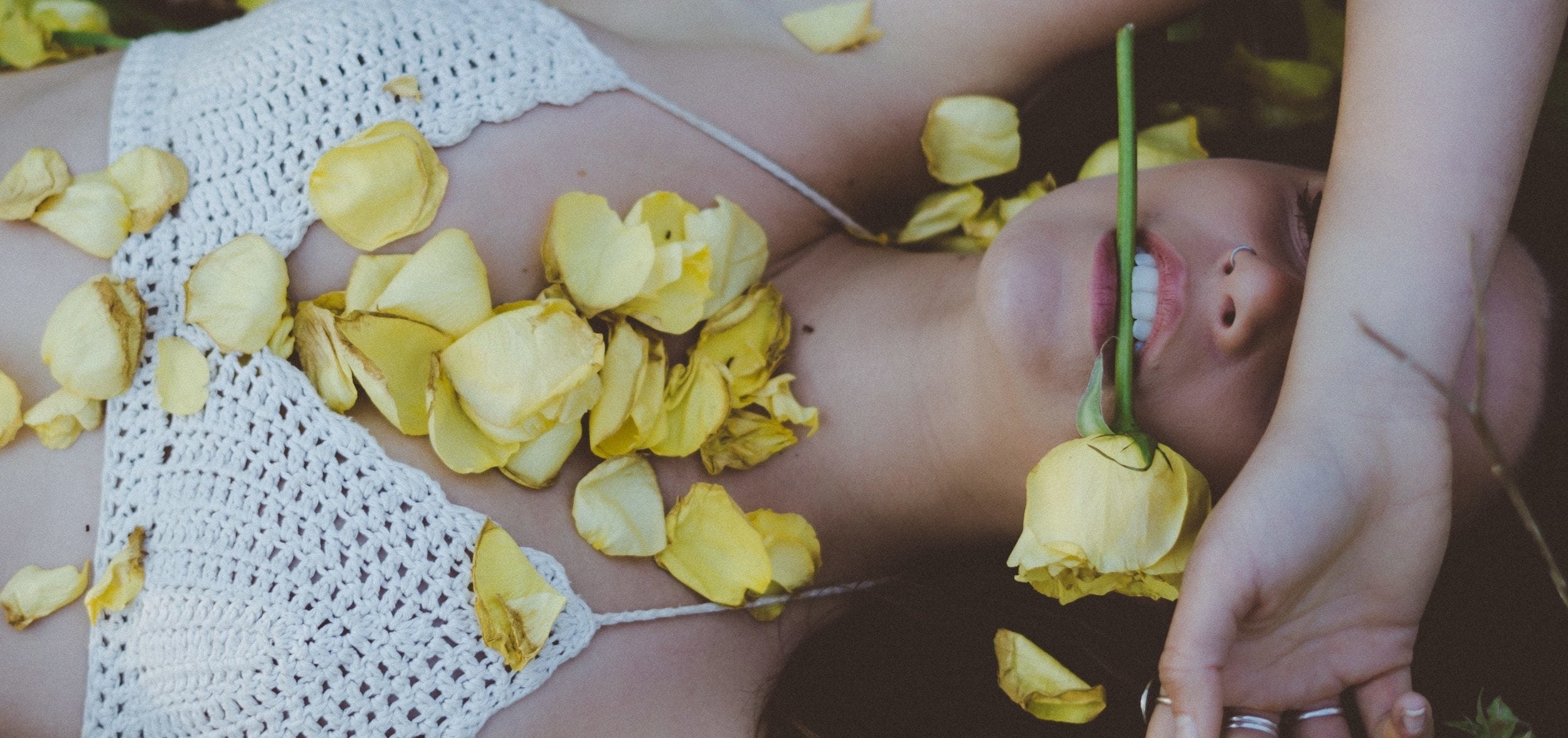 Jeune femme allongée dans l'herbe et couverte de fleurs