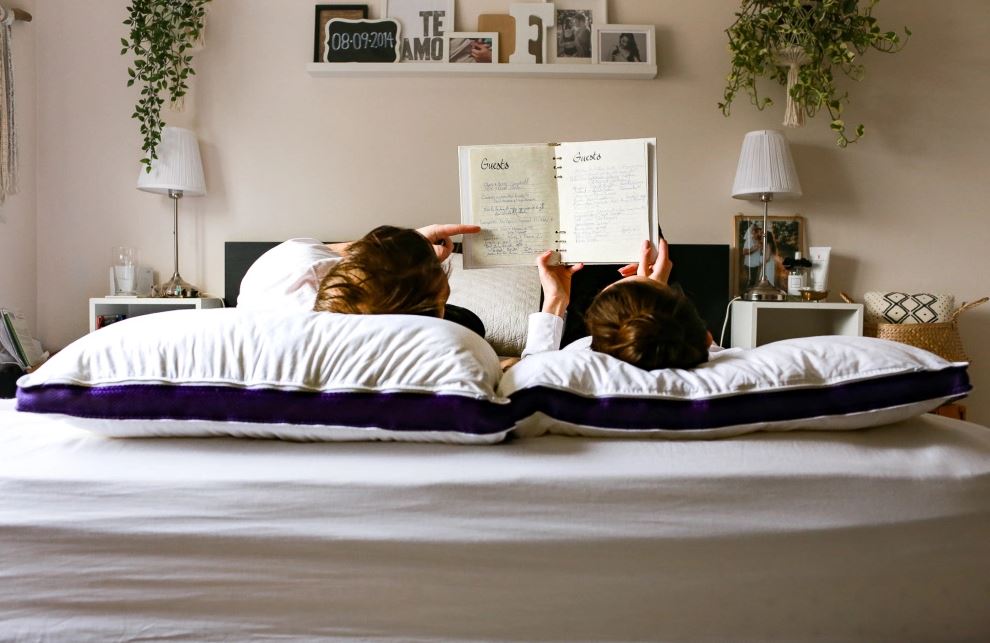 Deux clients lisent dans leur chambre sur leur matelas en mousse Polysleep avec l'oreiller Polysleep